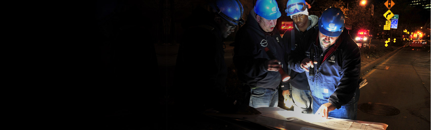 Workers using flashlights to view a diagram.