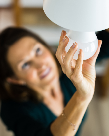 Una mujer instala una bombilla en una lámpara de techo.