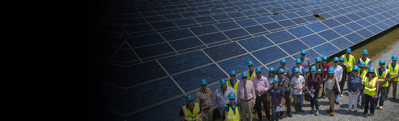 A team of Con Edison employees standing near a large solar panel installation