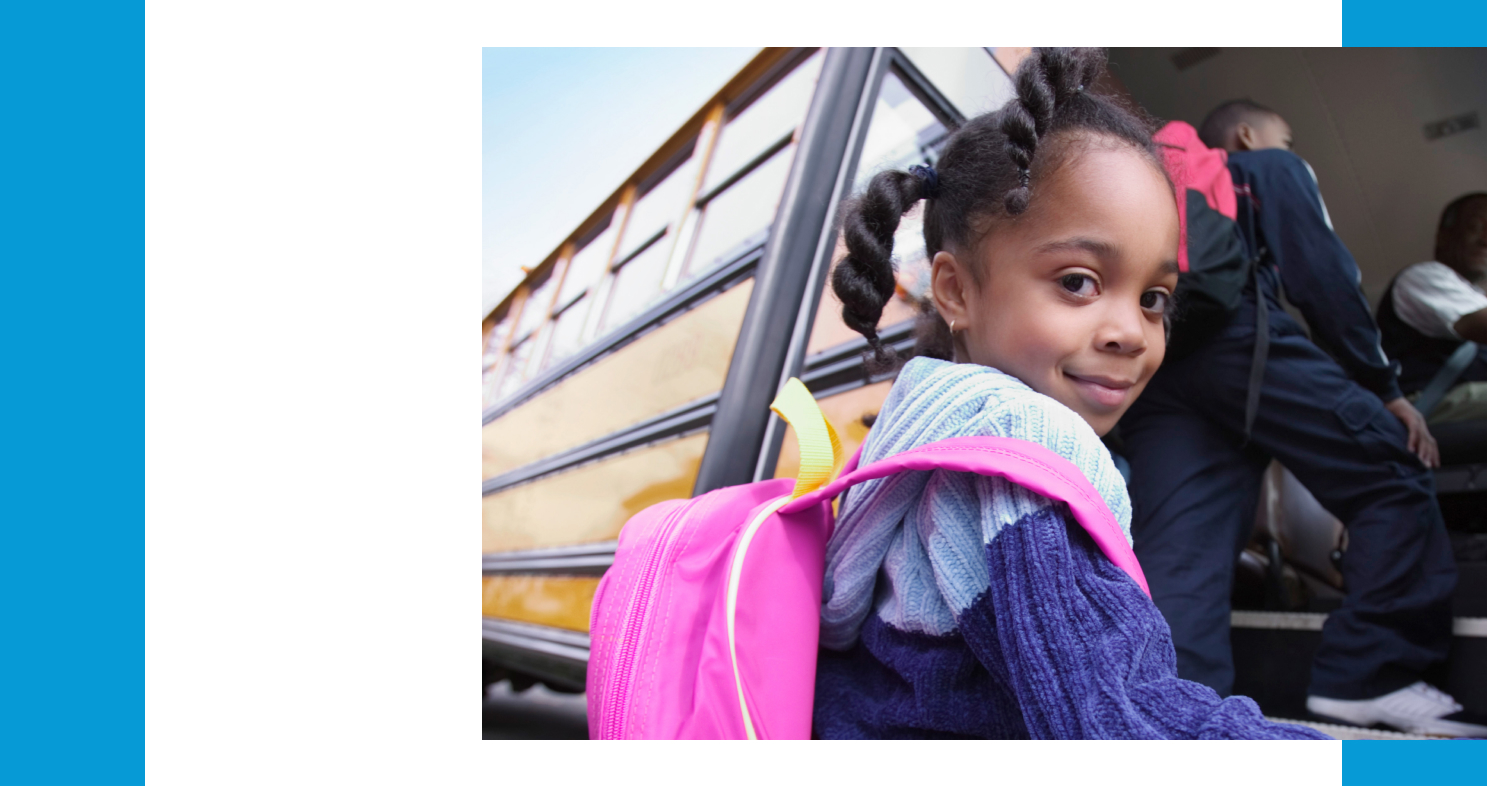 A young girl getting on a schoolbus.