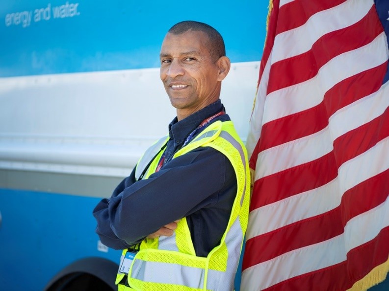 A utility worker posing next to an American flag.