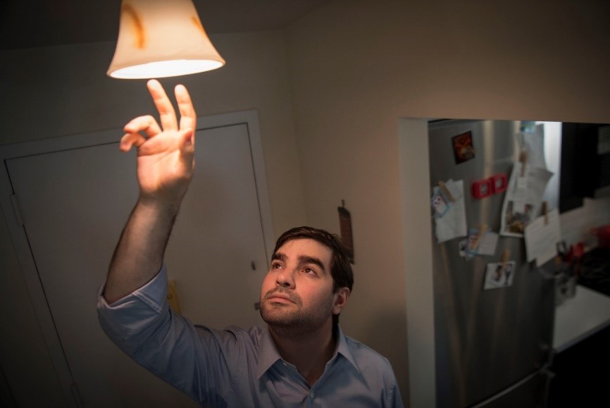 A person reaches up to a light fixture in their home.