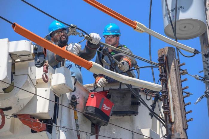 Dos trabajadores de Con Edison reparando equipos eléctricos aéreos.