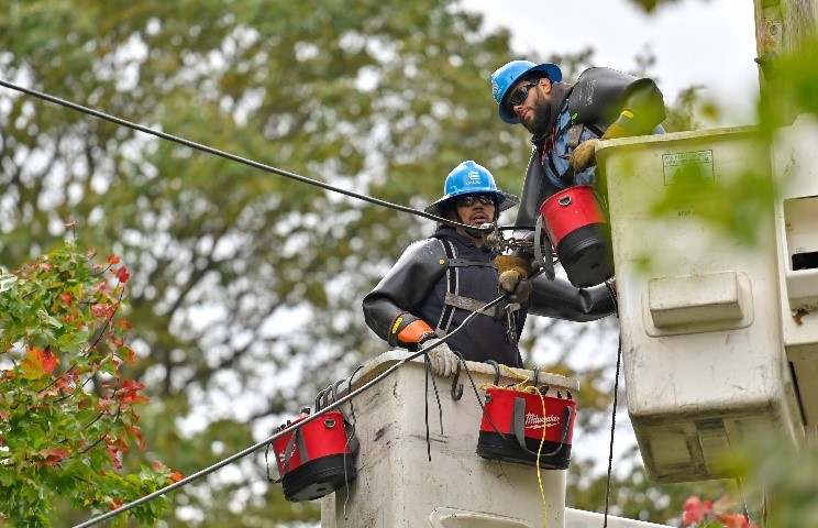 Two utility workers repair overhead power lines.