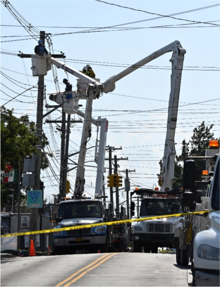 Varios trabajadores reparando cables eléctricos aéreos desde un camión grúa.