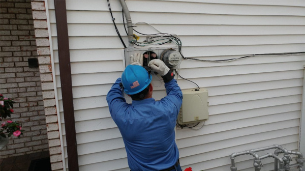 Un trabajador instalando un contador inteligente en una pared exterior.