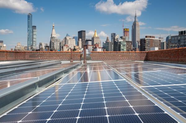 Paneles solares en una azotea con el horizonte de la ciudad de Nueva York de fondo.