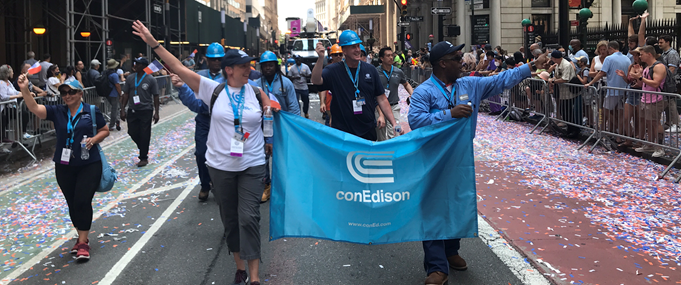 Con Edison workers holding a Con Edison banner in a parade. 