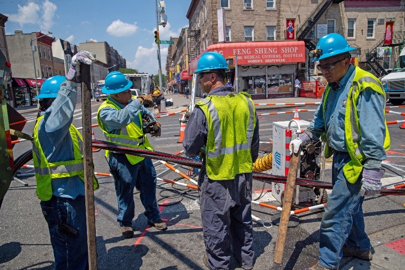 Four workers perform utility work on a city street.
