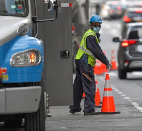 A utility worker placing safety cones on the street.
