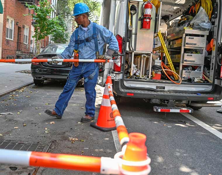 A utility worker sets up a safety barrier on a city street.