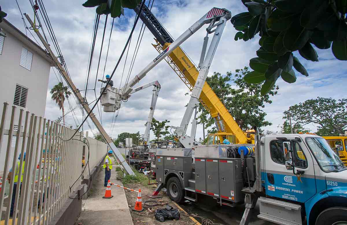 A Con Edison bucket truck parked along a street with downed powerlines.
