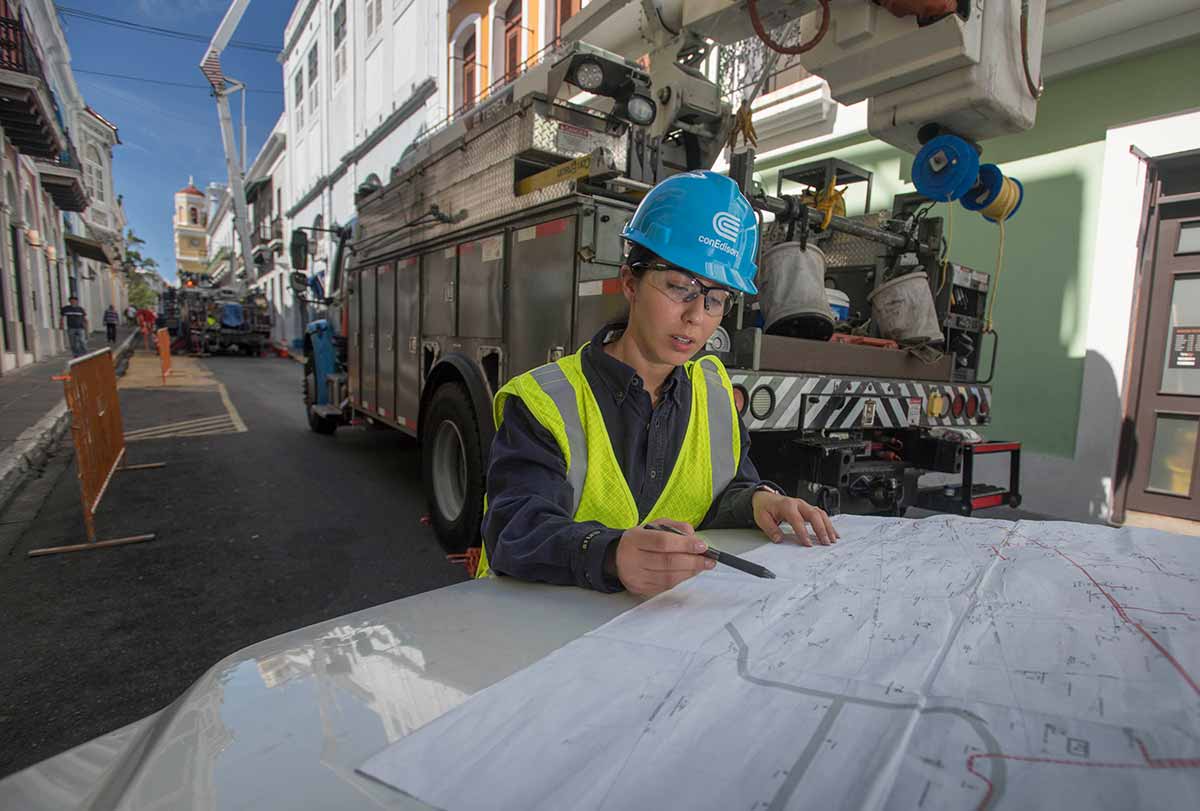 A Con Edison worker reviews plans on the hood of a truck.