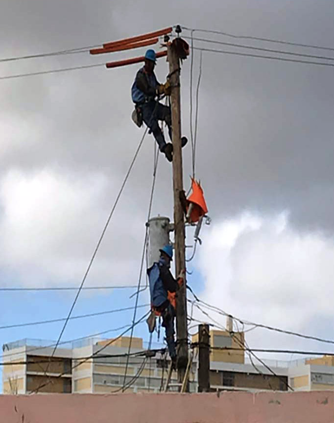 Con Edison workers climbing a utility pole to perform repairs.