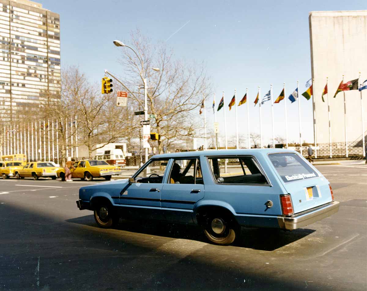 Vintage photo of a blue Con Edison car driving past the United Nations in New York City.