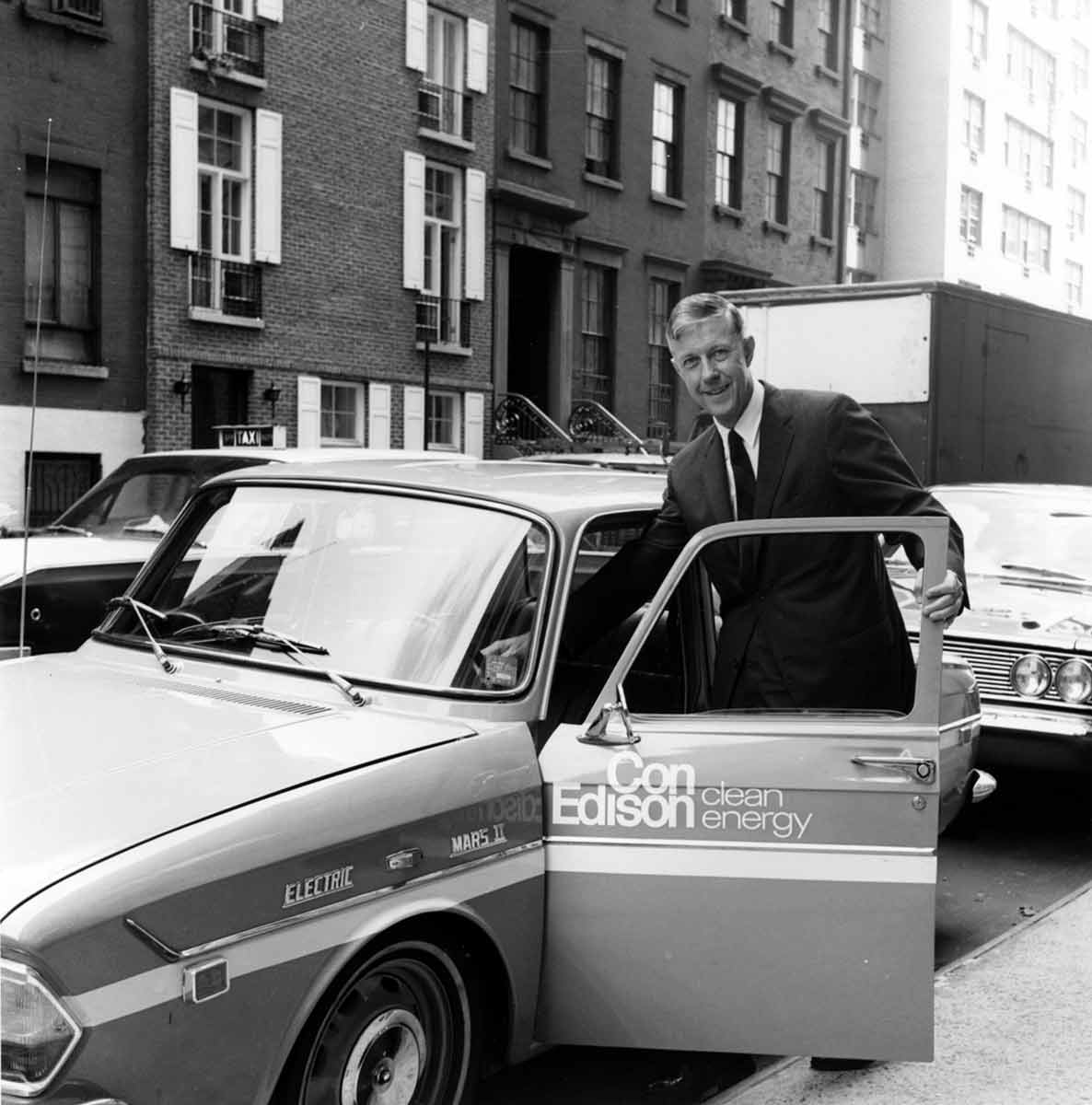 Black and white photo of a man getting into a Con Edison vehicle in New York City.