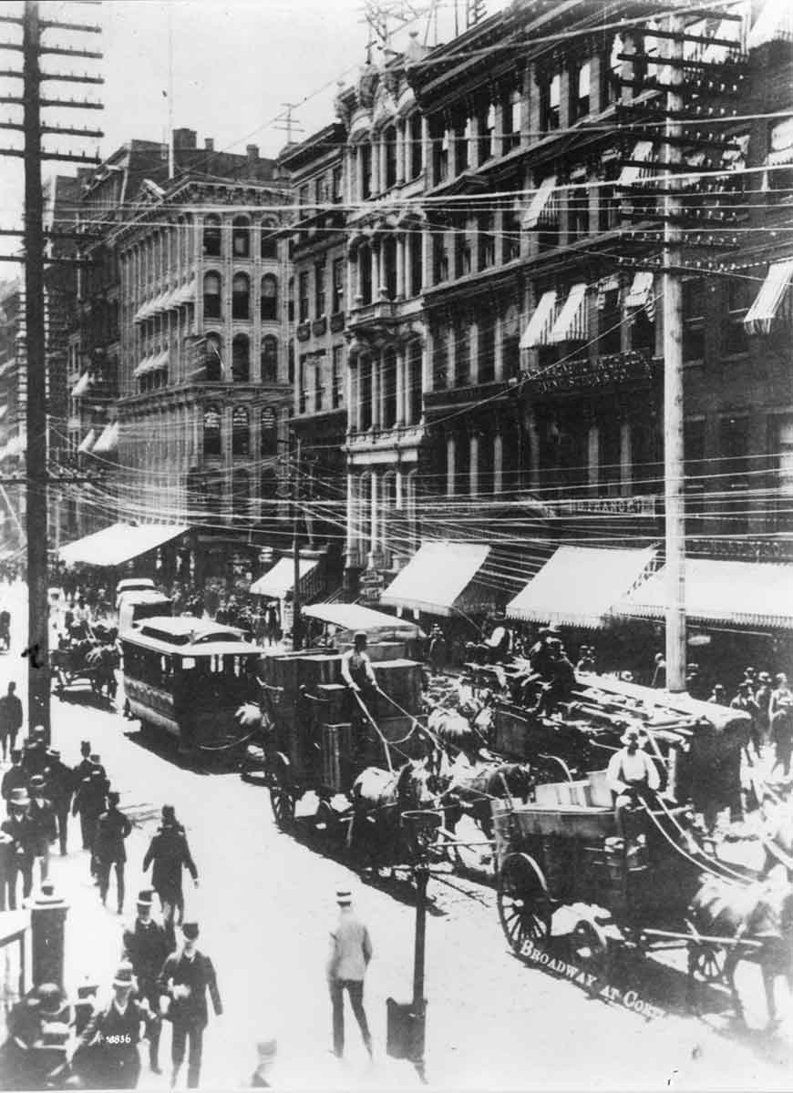 Fotografía antigua en blanco y negro de una calle de la ciudad de Nueva York con muchos postes para servicios públicos.