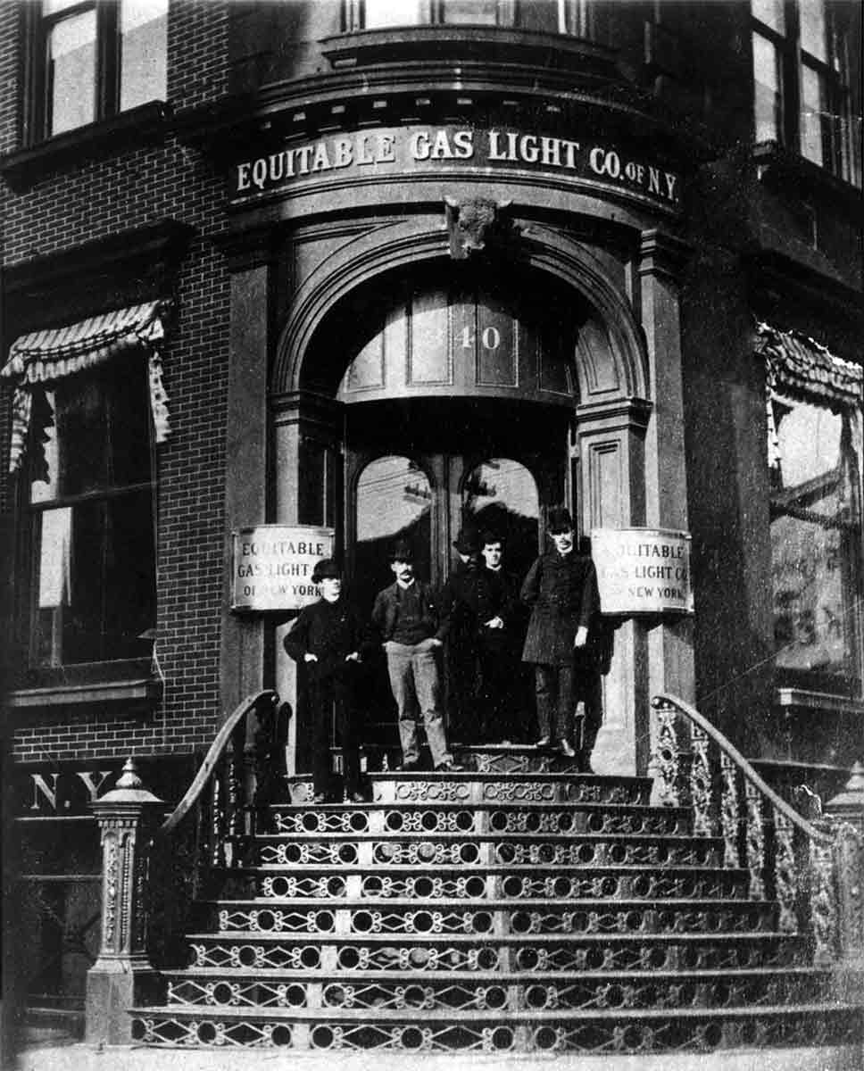 Black and white photo of workers standing in front of the Equitable Gas Light Company building's front entrance.