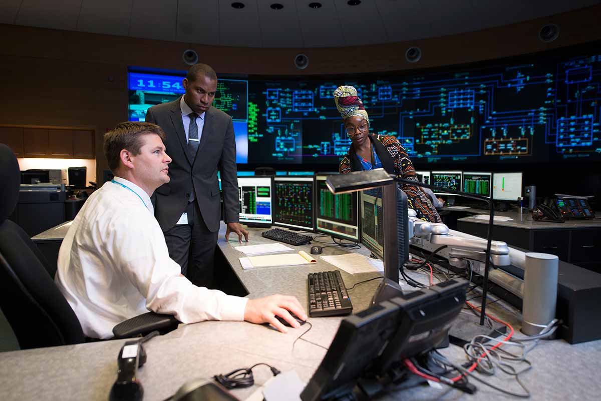 Tres empleados de Con Edison en una sala de control supervisando el sistema de red.