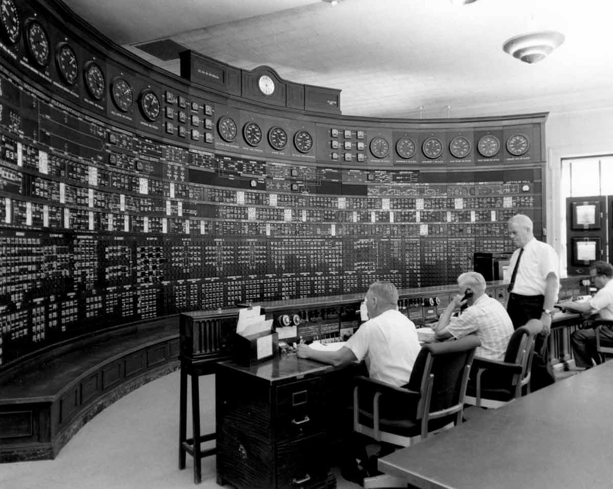 Historic photo of four Con Edison workers inside a monitoring station room. 