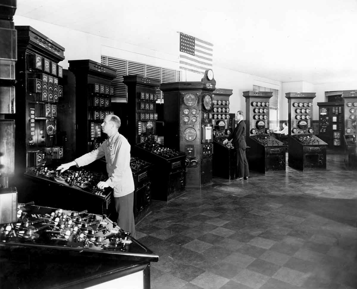 Fotografía en blanco y negro de trabajadores de Con Edison en estaciones de monitoreo de servicios públicos.