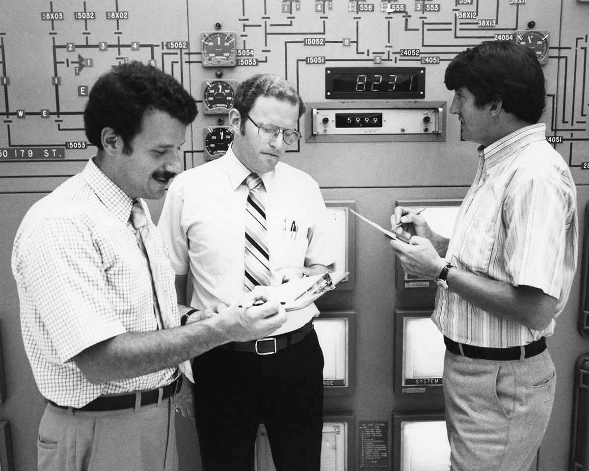 Tres empleados de Con Edison en la sala de control de un centro de energía.