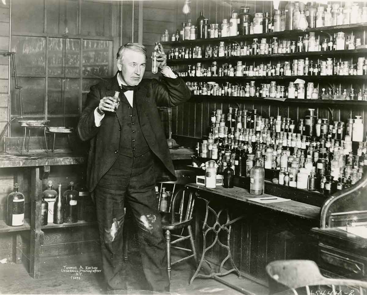 Black and white photo of Thomas Edison working in a laboratory.