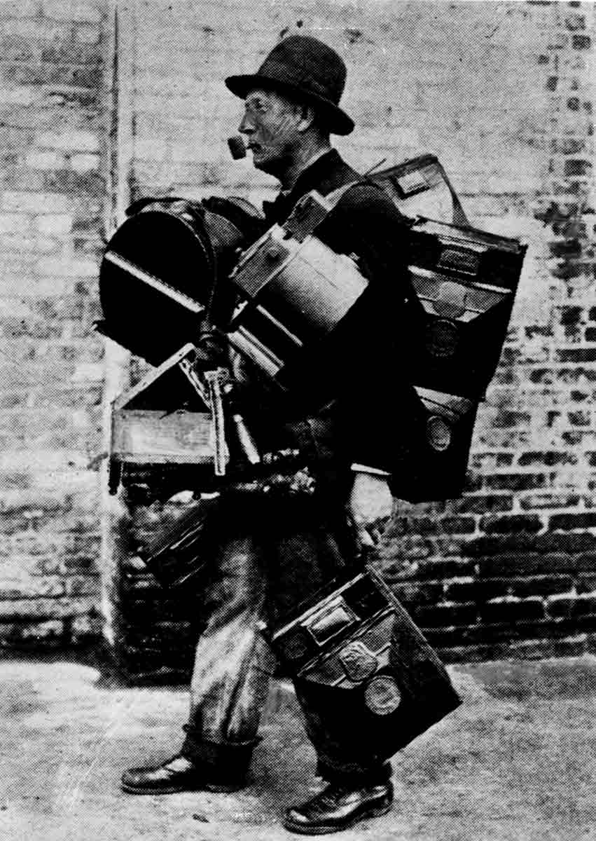 Vintage photo of a man holding several pieces of equipment.