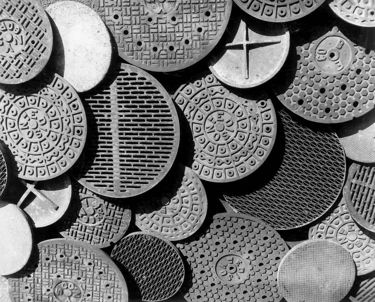 Black and white photo of several manhole covers.