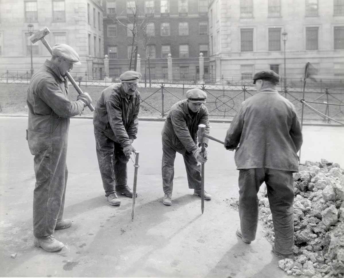 Fotografía en blanco y negro de cuatro trabajadores de Con Edison preparándose para excavar en una calle de la ciudad.
