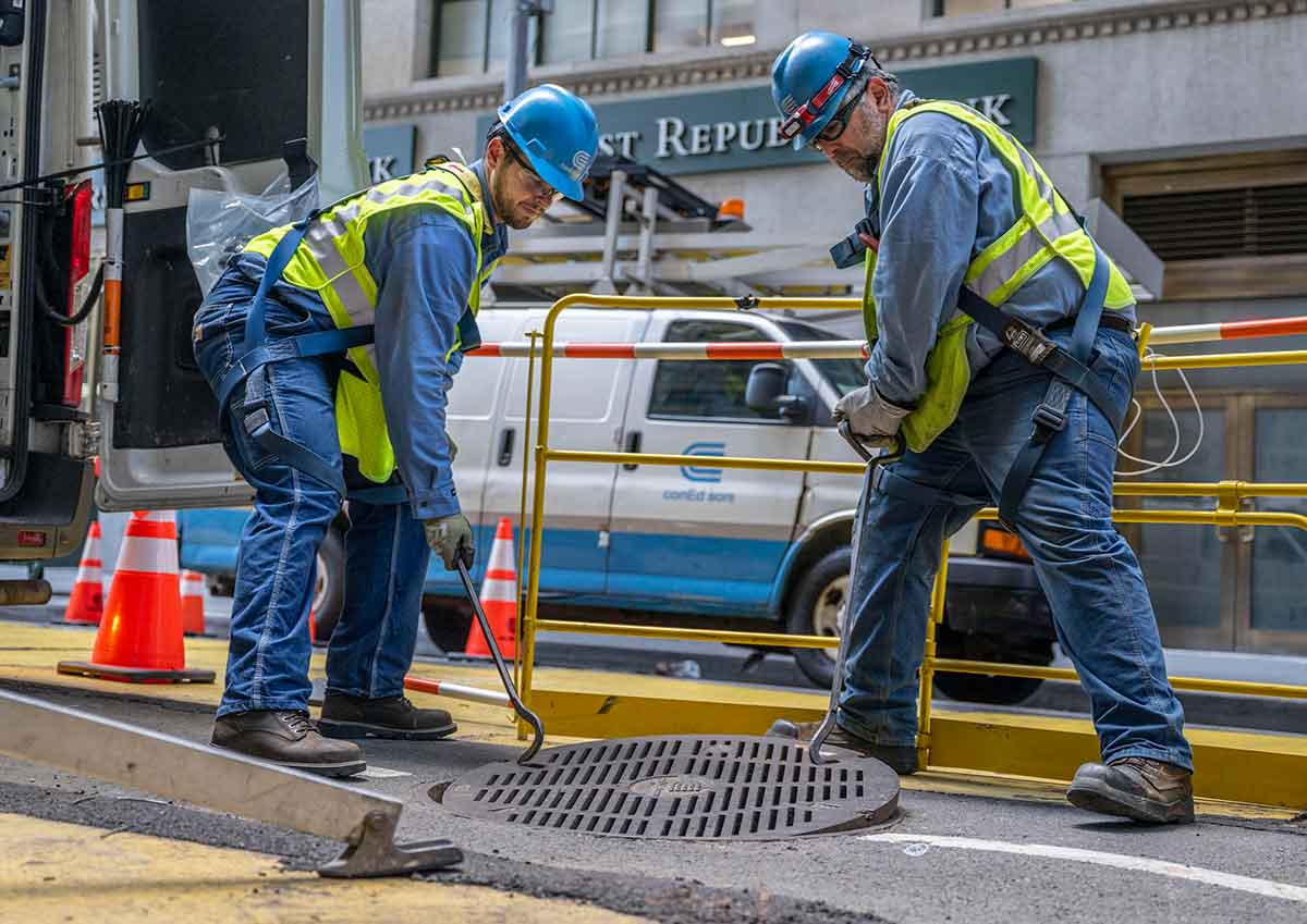 Con Edison electric crews lift up a manhole on a city street.