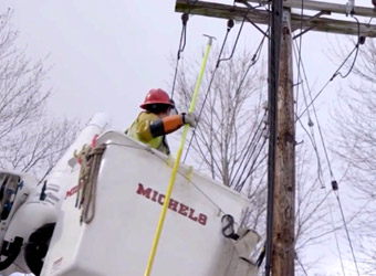 Trabajador de Michael's Power reparando cables eléctricos en un poste telefónico.
