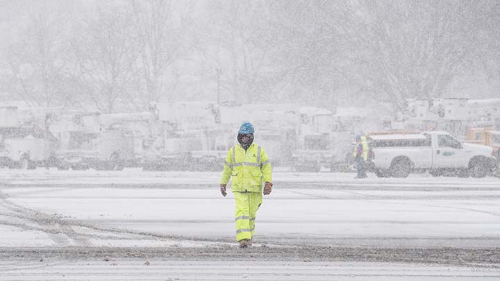 Un trabajador de Con Edison camina por un área de preparación de recuperación cubierta de nieve.