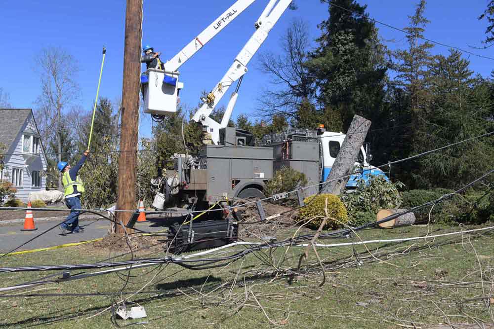 Un trabajador en un camión grúa reparando los daños a los postes después de las tormentas Riley y Quinn. 