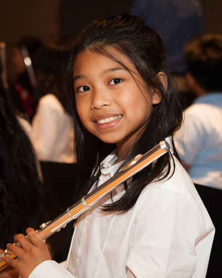 A young woman stands with a flute resting on her shoulder.