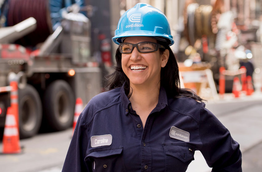 Una empleada de Con Edison sonríe mientras se encuentra en una calle de la ciudad cerca de una obra.