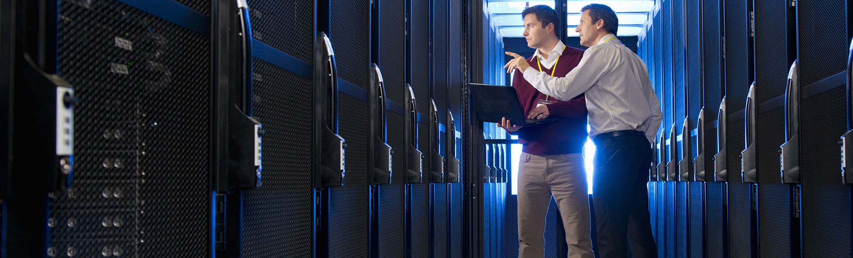 Two people standing near computer servers