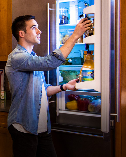 A man standing in front of an open refrigerator. 
