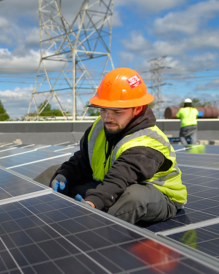 An Orange and Rockland employee working on a solar panel installation on a rooftop.