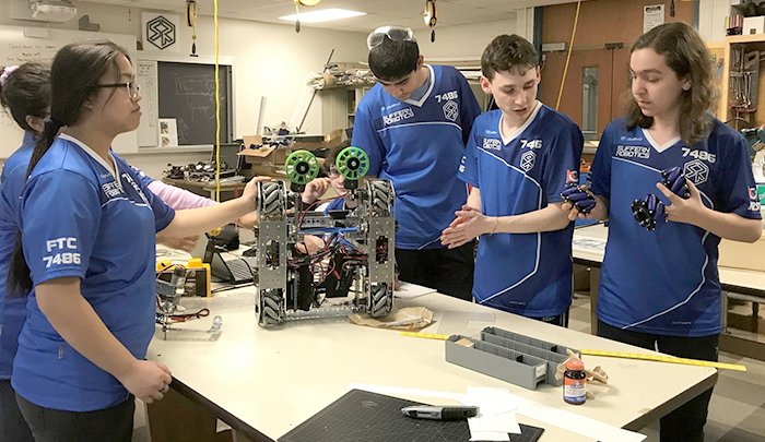 Pictured here, upgrading the wheels on a robot in the team’s Suffern lab are, from left: Ahtziri Lopez (partially blocked), Vicky Chu, Mark Medjelian (partially sitting), Logan Larrondo, Jason Kardon and Ron Guter.