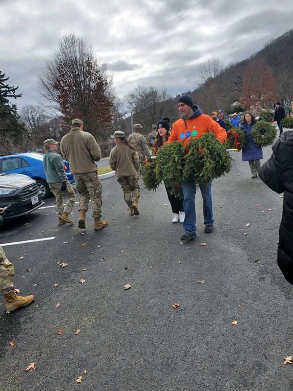Volunteers carrying holiday wreaths. 