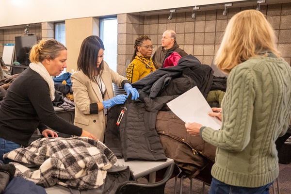 A group of people sorting through winter coats. 