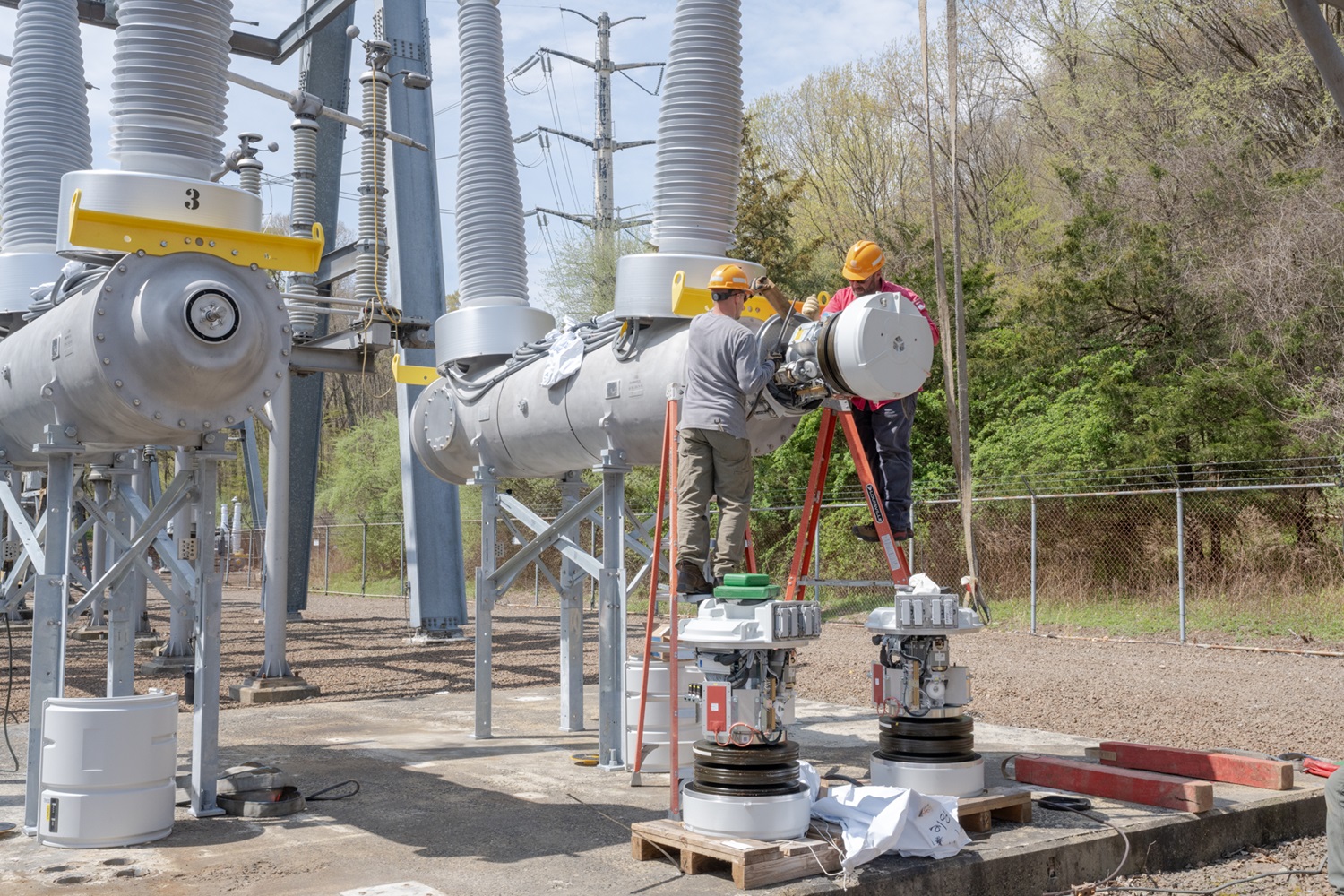 Two utility employees working at a substation. 