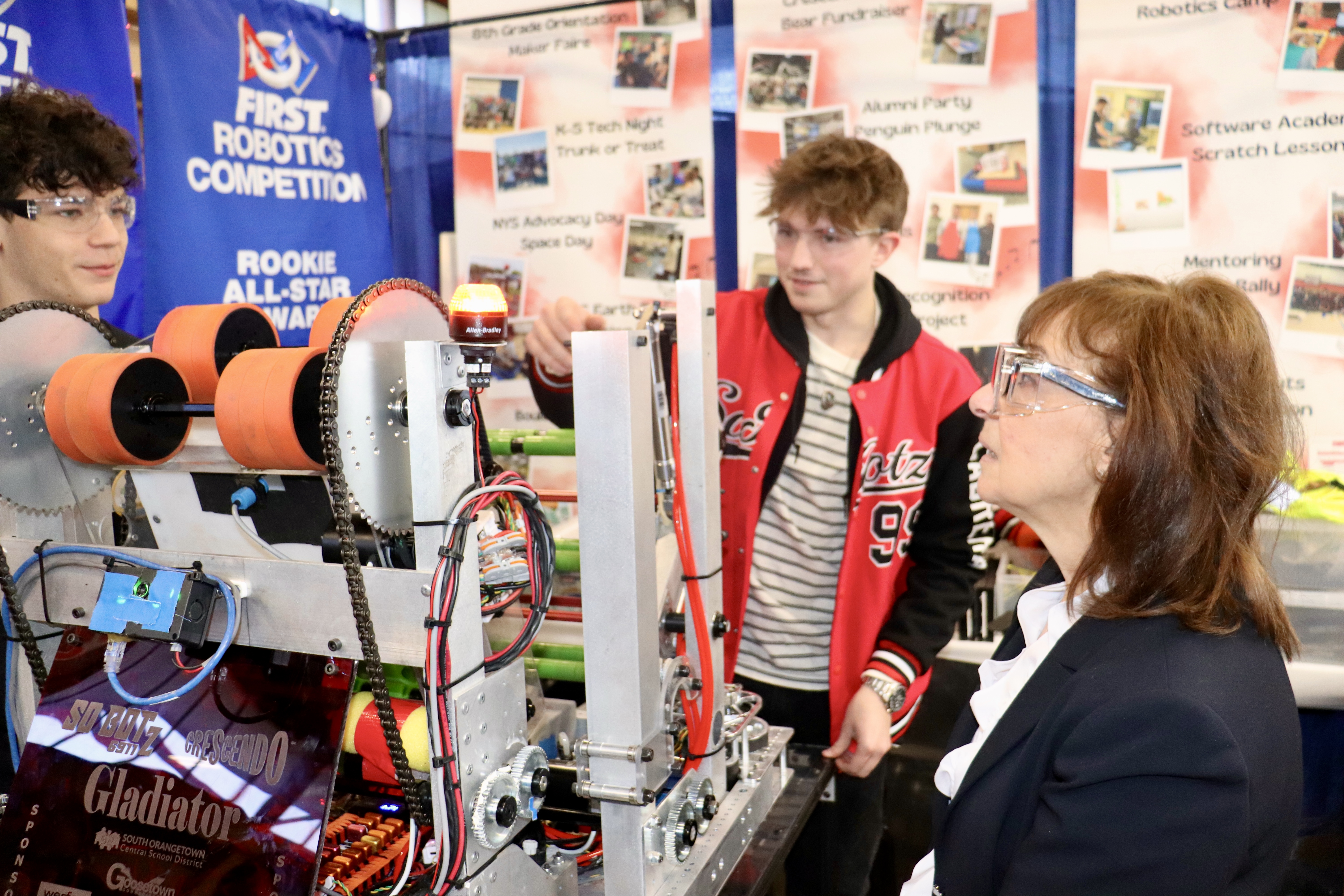 Three individuals look over robotic equipment. 